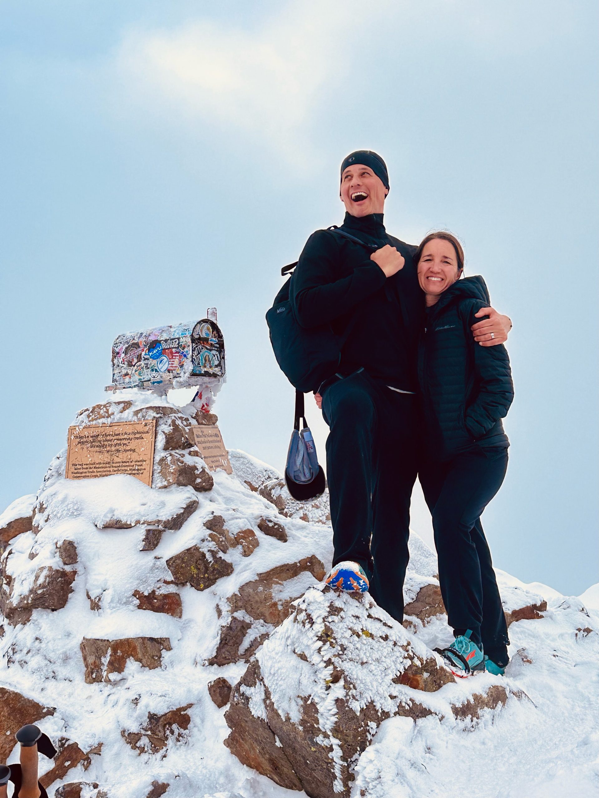Couple standing on snowy peak with mailbox statue