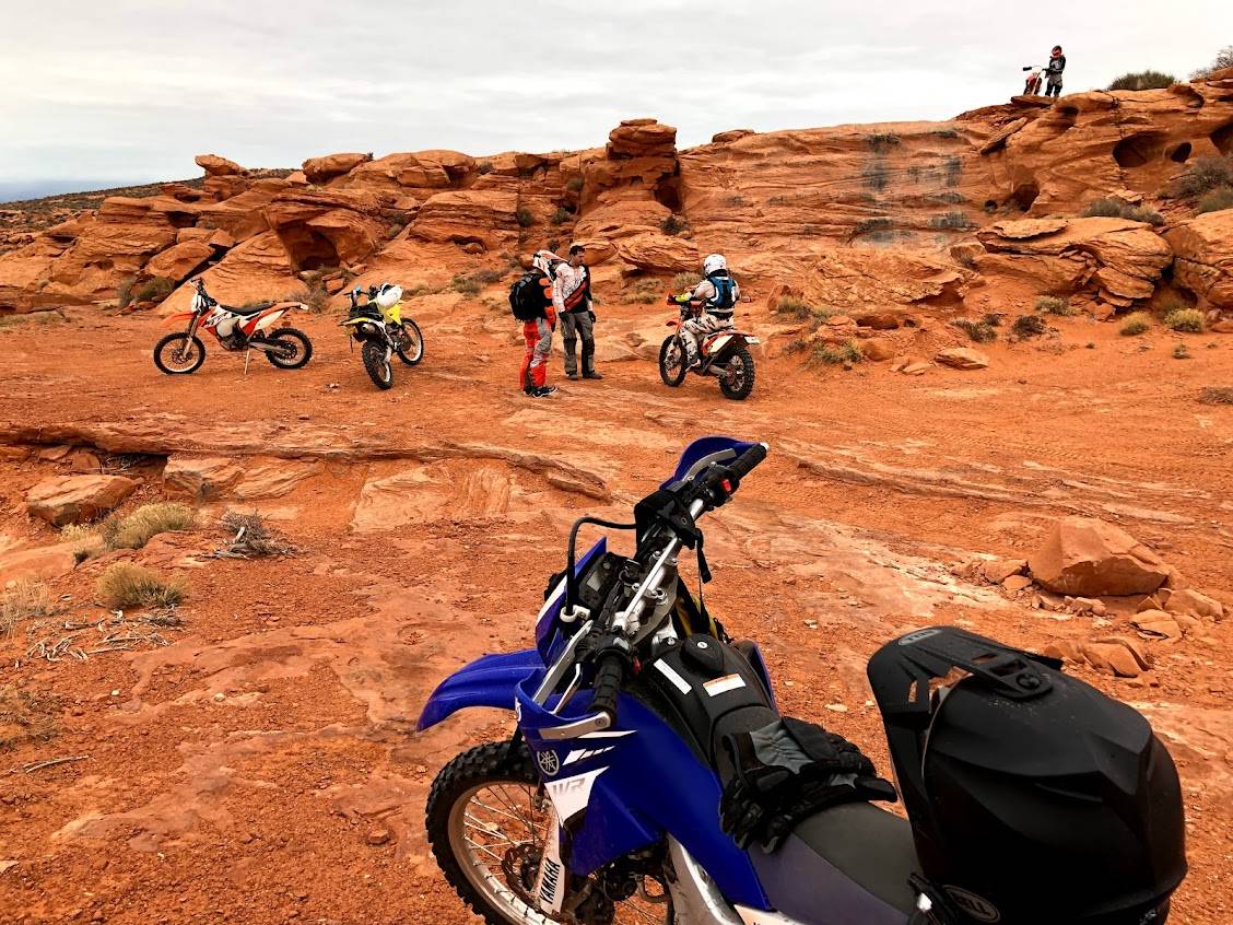 Motorbikes and riders in red desert rock landscape