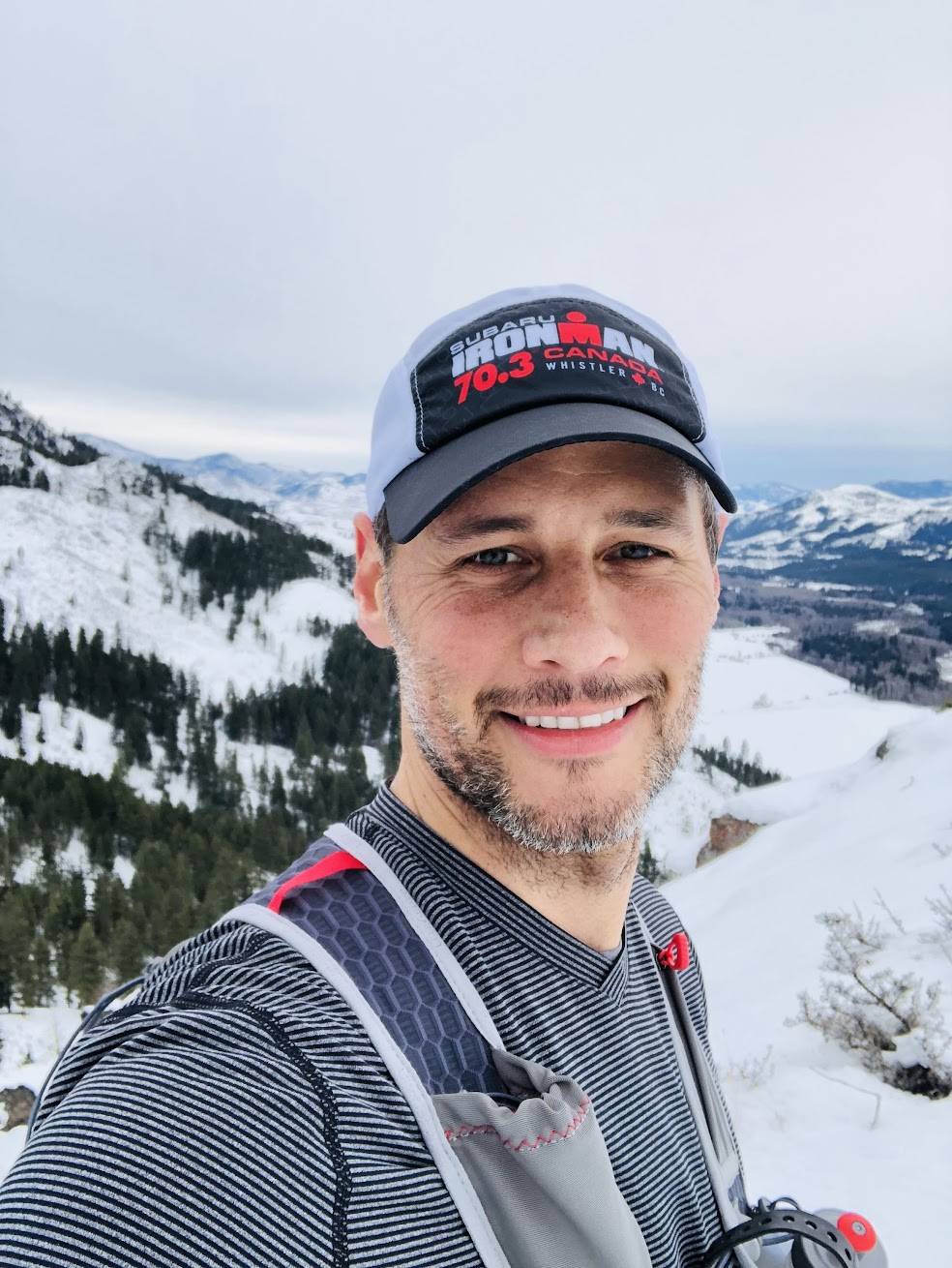 Smiling man in hat on snowy mountain trail