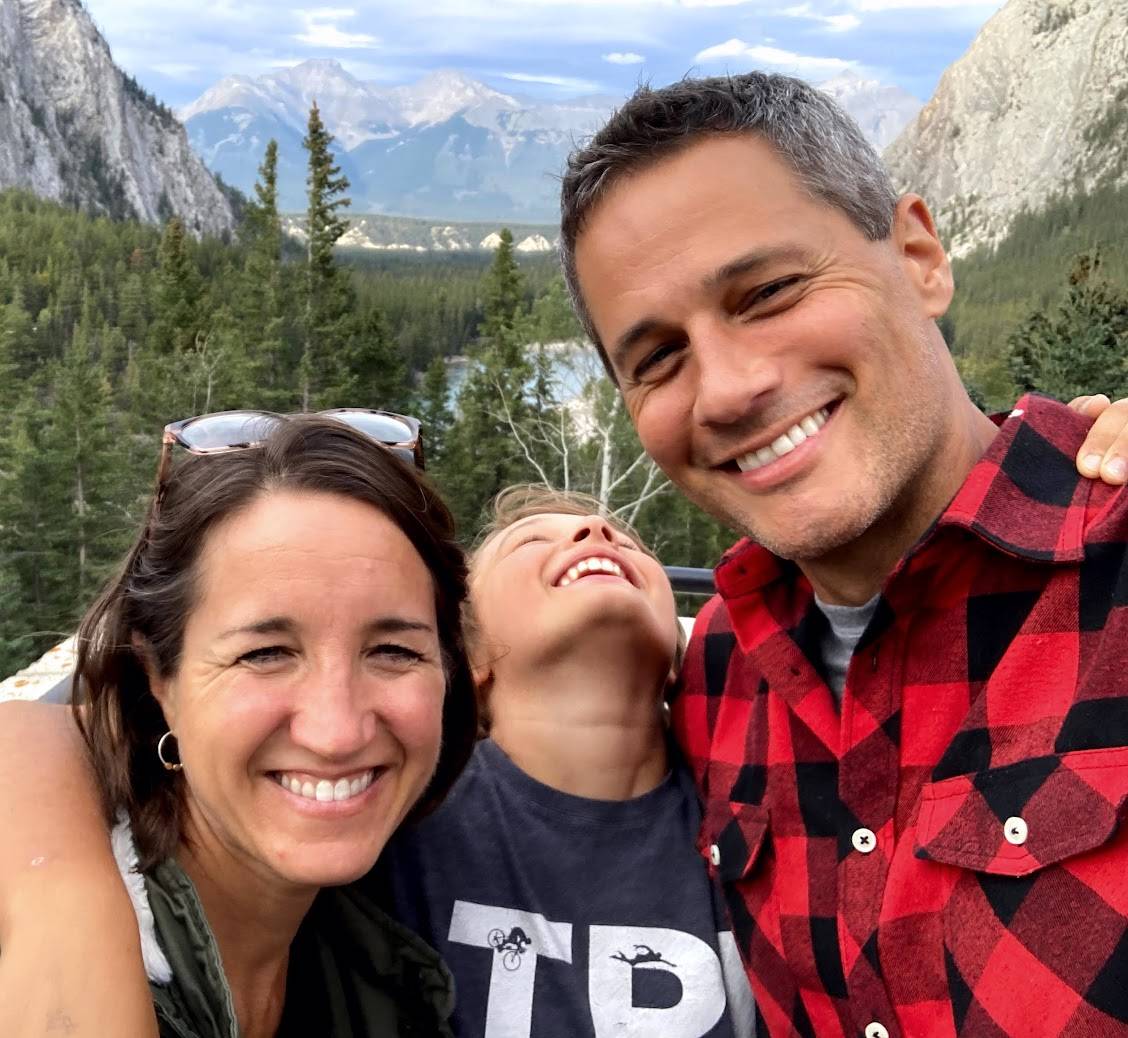 Smiling family selfie outdoors in mountains and forest.