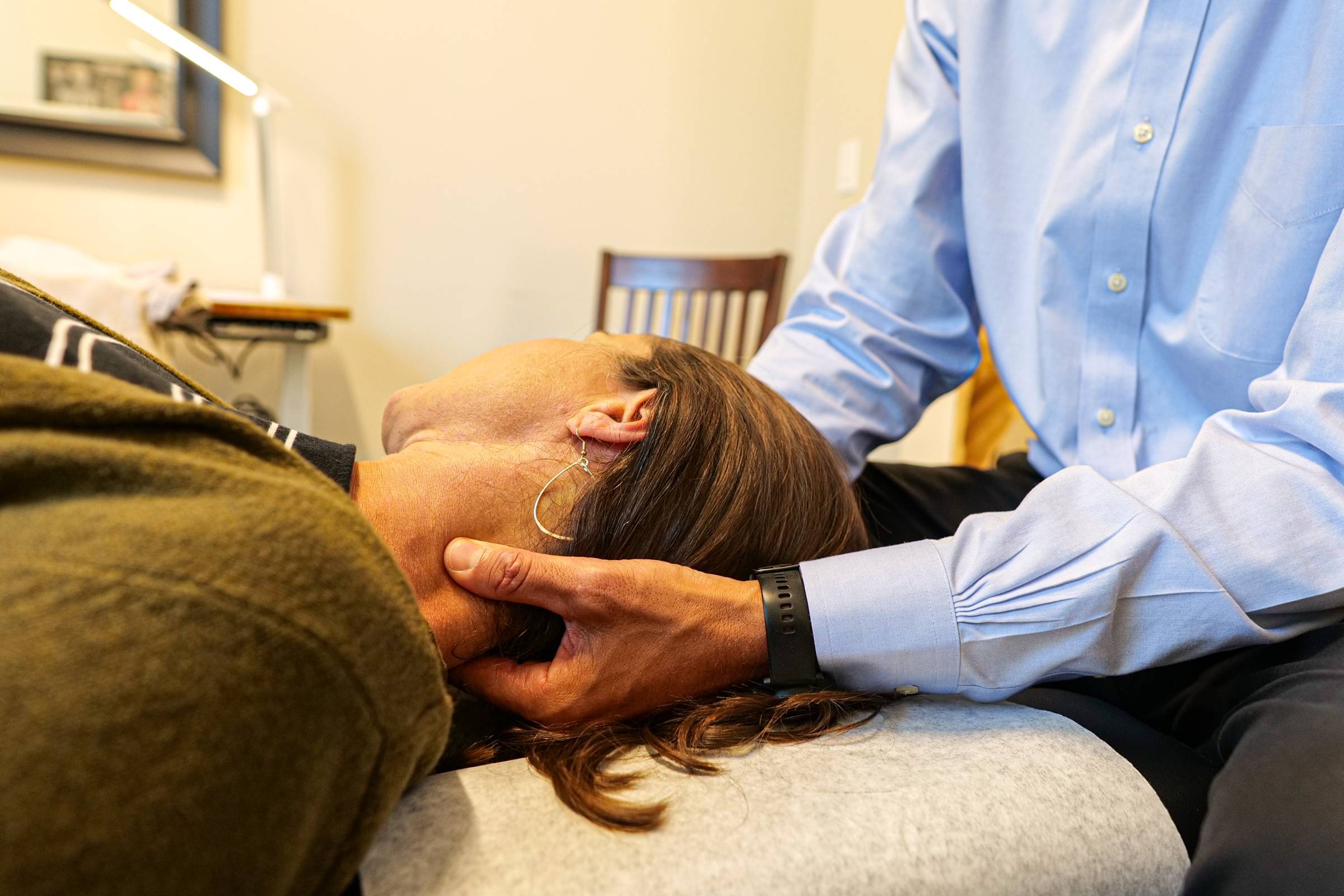 Person lying down while a clinician supports the head with hands.