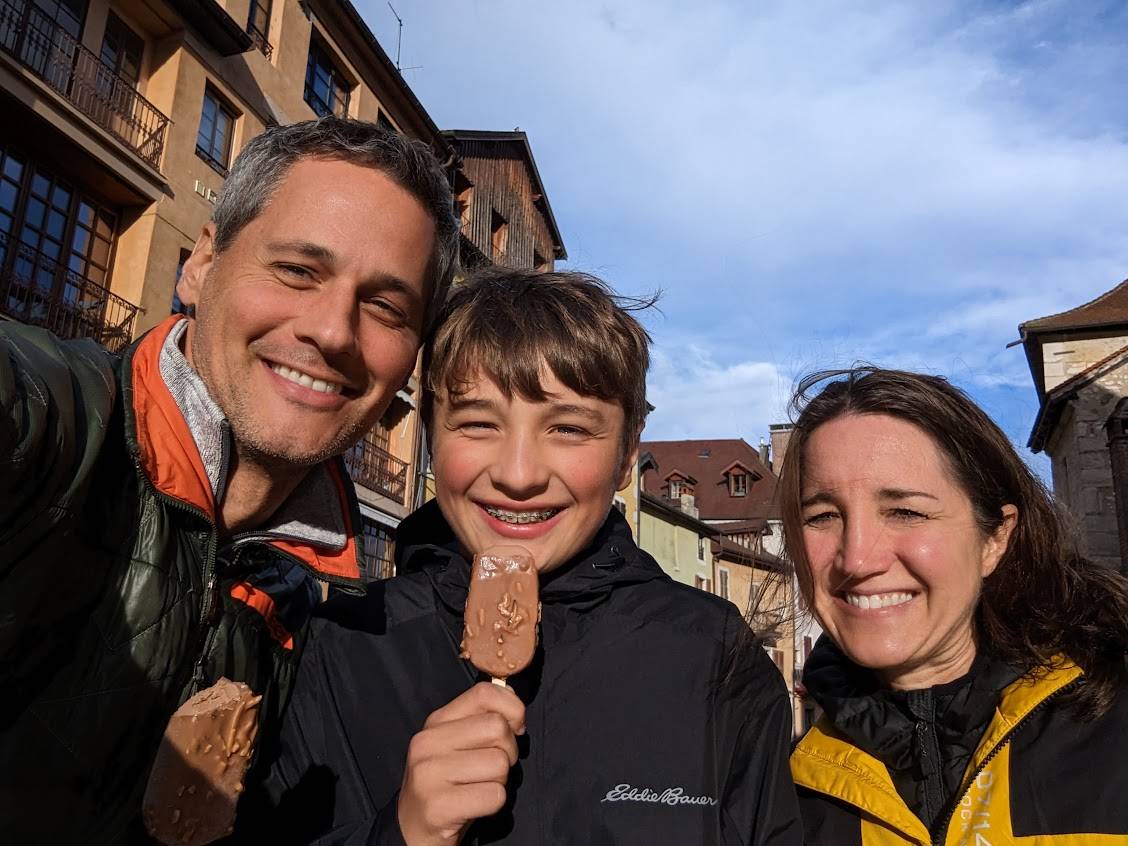 Smiling family posing outdoors, holding chocolate ice pops. 