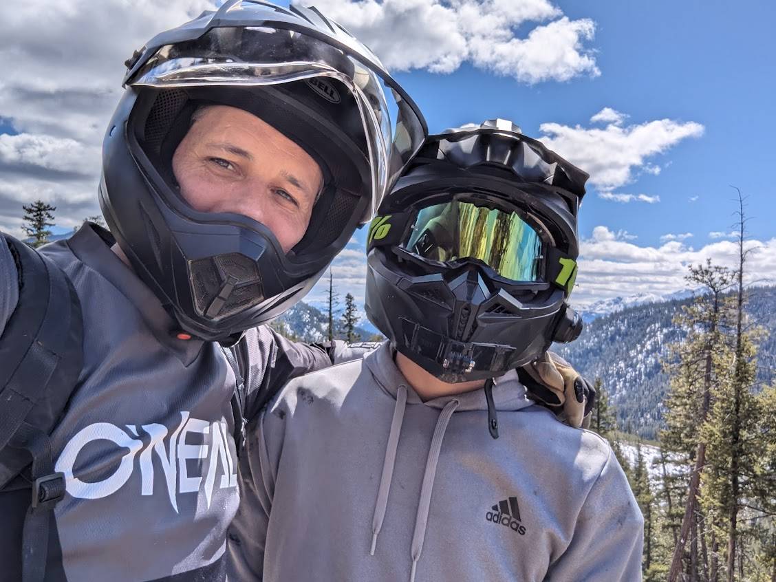 Two people wearing helmets on a snowy mountain landscape