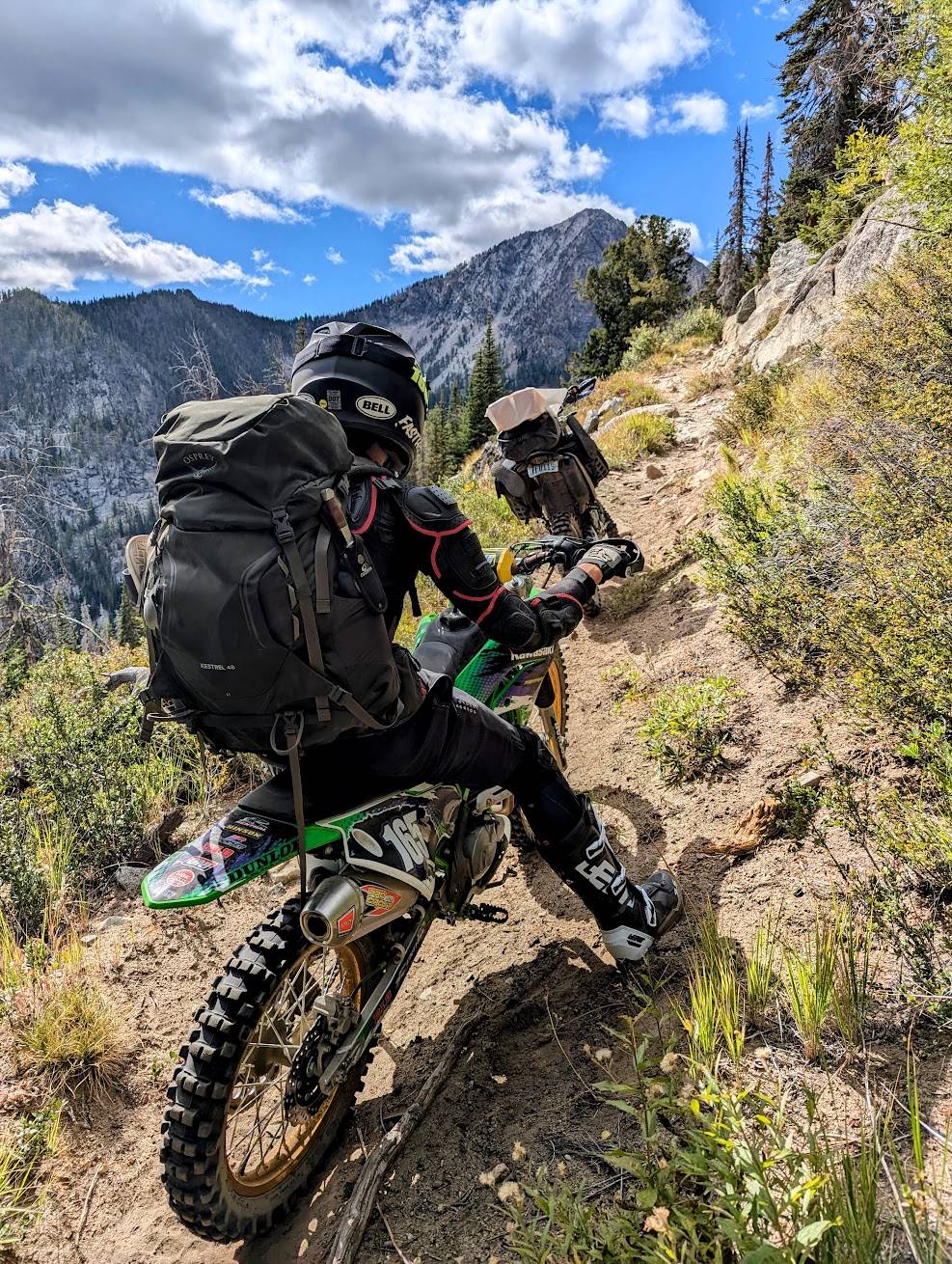 Motorcyclist on a dirt trail with backpacked gear